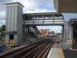 railway station with bridge going over tracks. Safety barriers and signs fitted to the right 